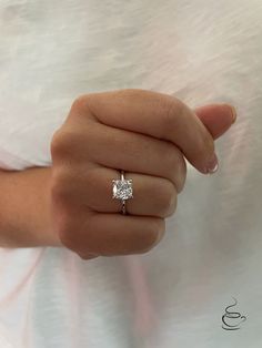 a woman's hand with a diamond ring on her finger, showing the center stone