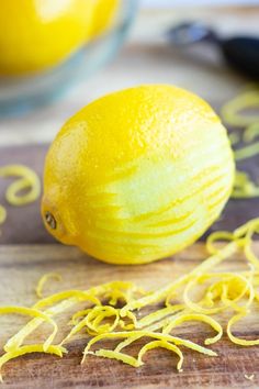 a yellow lemon sitting on top of a wooden cutting board