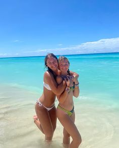 two women in bikinis hugging on the beach