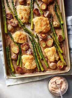 asparagus, potatoes and parmesan bread on a baking sheet with dipping sauce