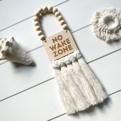 a wooden sign that says no wake zone next to two seashells on a white wood floor