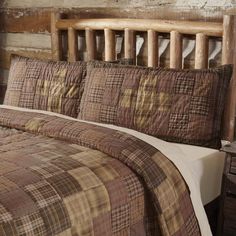 a bed with brown and tan plaid comforter in a rustic style bedroom, next to an old wooden headboard