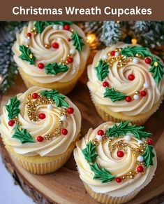 christmas wreath cupcakes with white frosting and red berries on top sitting on a wooden platter