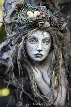 a statue is adorned with twigs and eggs in the shape of a woman's head