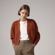 a woman wearing a brown cardigan and checkered pants with her hands on her hips