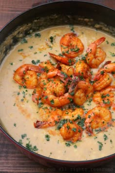 a bowl filled with shrimp and grits on top of a wooden table