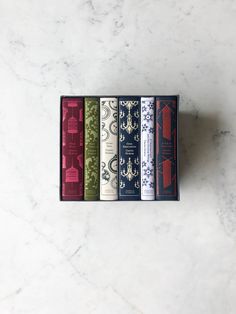 four books in a box on a marble surface