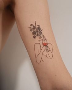 a woman holding a wine glass with flowers on her arm