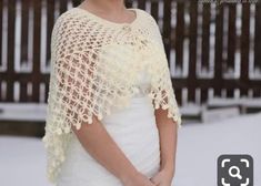 a woman standing in the snow wearing a crocheted shawl and white dress