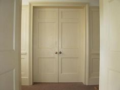 an empty hallway with two white doors and carpet