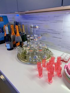 there are many bottles and glasses on the counter with drinks in them, along with an ice tray