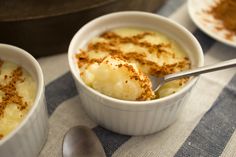 three small bowls filled with food on top of a blue and white table cloth next to two spoons