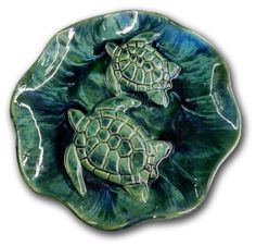 two green turtles sitting on top of a leafy bowl