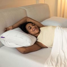 a woman laying on top of a white pillow