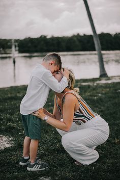 a man and woman kissing in front of a body of water