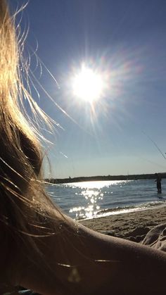 the back of a woman's head as she flies a kite at the beach