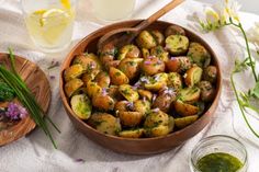 a wooden bowl filled with potatoes on top of a table next to other dishes and utensils