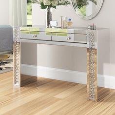 a mirrored console table with flowers on it in front of a large mirror and window