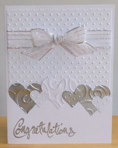 a white card with two hearts and a bow on the front that says congratulationss