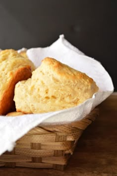 two pieces of bread in a basket on a wooden table with white napkins around it