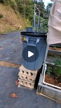 a blue trash can sitting on top of a pile of bricks