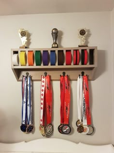 several medals are hanging on a shelf with ribbons