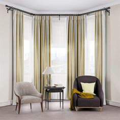 a living room with two chairs and a table in front of the window that has curtains on it