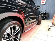 a black car parked in a garage next to a toolbox and some tools on the floor