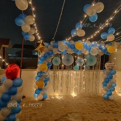 balloons and streamers are hanging from the ceiling in front of a party arch at night