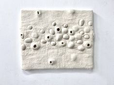 a white wall with holes in the middle and small circles on it's surface