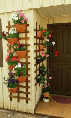 several potted plants are hanging on the side of a building with wooden slats