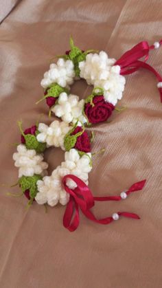 two wreaths with red ribbons and white flowers on a brown cloth covered tablecloth