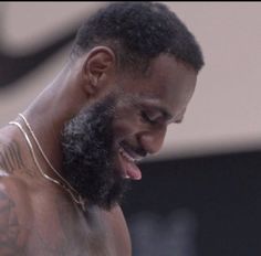 a close up of a man with a beard and tattoos on his chest smiling at the camera