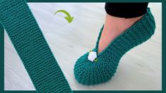 a woman's feet wearing green knitted slippers with a button on the side