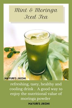 a green drink sitting on top of a table next to a napkin and some leaves