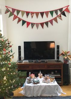 a living room with a christmas tree, television and table set up for an event