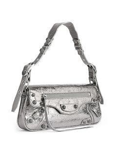 Find BALENCIAGA Le Cagole Sling Bag on Editorialist. The Balenciaga Le Cagole Sling Bag is crafted from metallized Arena lambskin. The bag features a studded magnet closure, a front zipped pocket with knotted leather puller, and aged-silver hardware. It has one main compartment, one inner patch pocket, and one zipped back pocket with knotted leather puller. The bag is lined in cotton canvas and made in Italy. The adjustable shoulder strap has a drop of 8.3 inches. The bag measures L 11.8 inches Small Sling Bag, Sling Bag Black, Balenciaga Women, Balenciaga Bag, Small Shoulder Bag, Leather Design, Blue Bags, White Bag, Silver Hardware