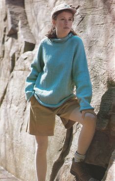 a woman standing on top of a rock next to a cliff