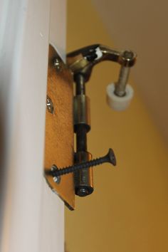 a close up of a door handle and latch on a white door with a yellow wall in the background