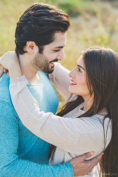 a man and woman standing next to each other with their arms wrapped around each other