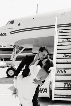 a bride and groom kissing in front of an airplane