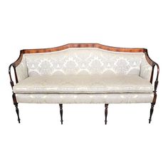 a white couch with wooden legs and an ornate upholstered back, against a white background