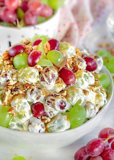 a bowl filled with fruit salad next to grapes