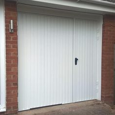 a white garage door is open on a brick building