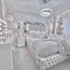 a bedroom decorated in white and silver with christmas decorations on the wall, bed, dresser and mirror