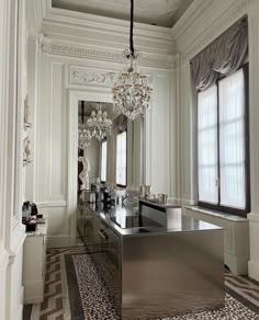 an elegant bathroom with chandelier, mirror and tiled flooring in the room