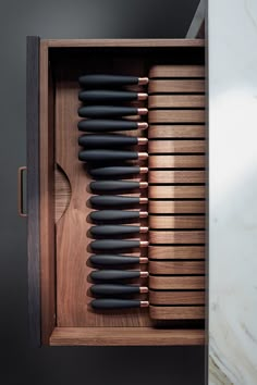 a wooden box with black utensils in it