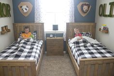 two small children are laying in their twin beds with checkered blankets on them and teddy bears hanging above the bed