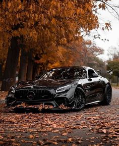 a black sports car parked on the side of a road in front of some trees