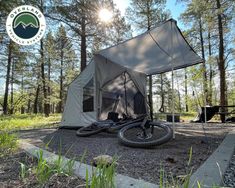 a tent in the woods with a bicycle parked next to it